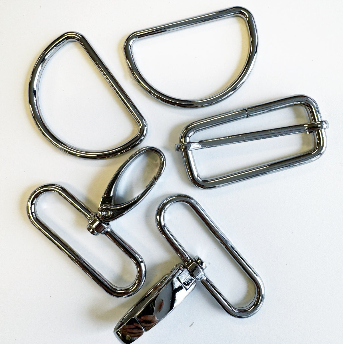 Five metal buckles of different shapes and sizes on a white background