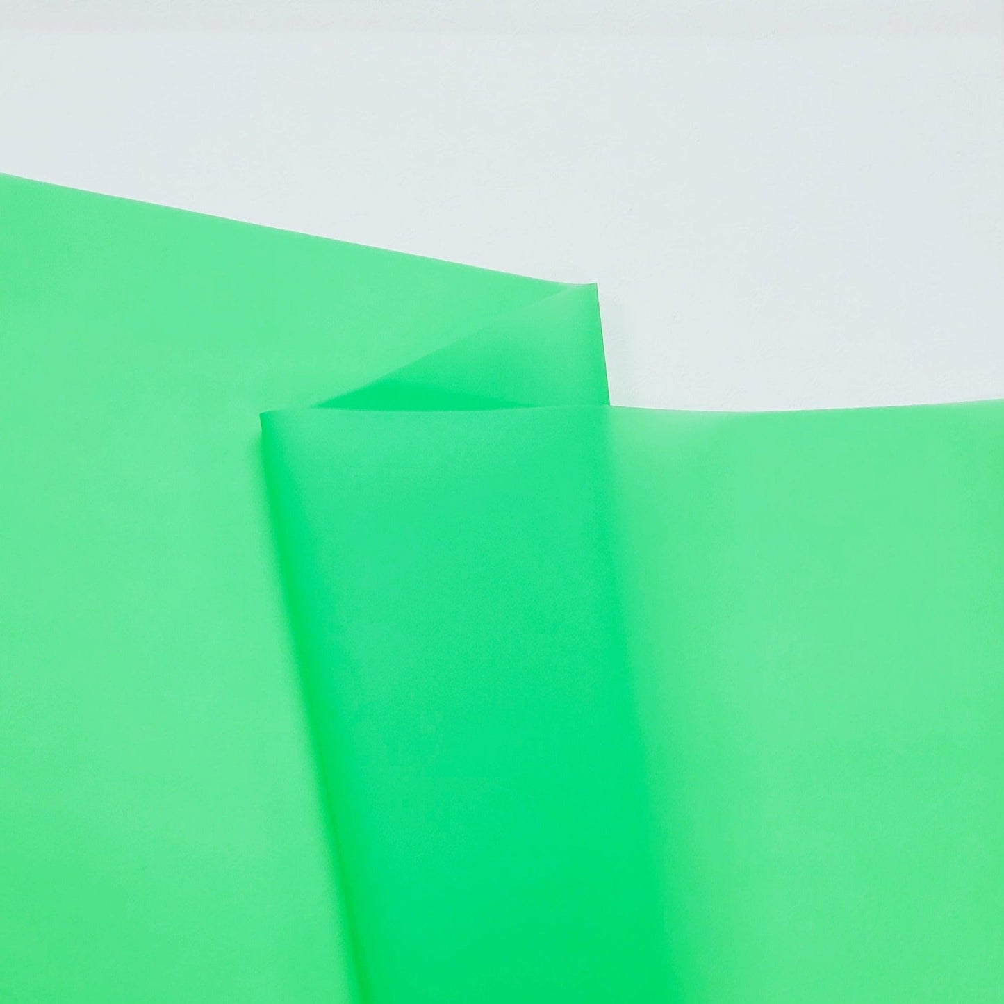 Two overlapping green sheets of paper on white.