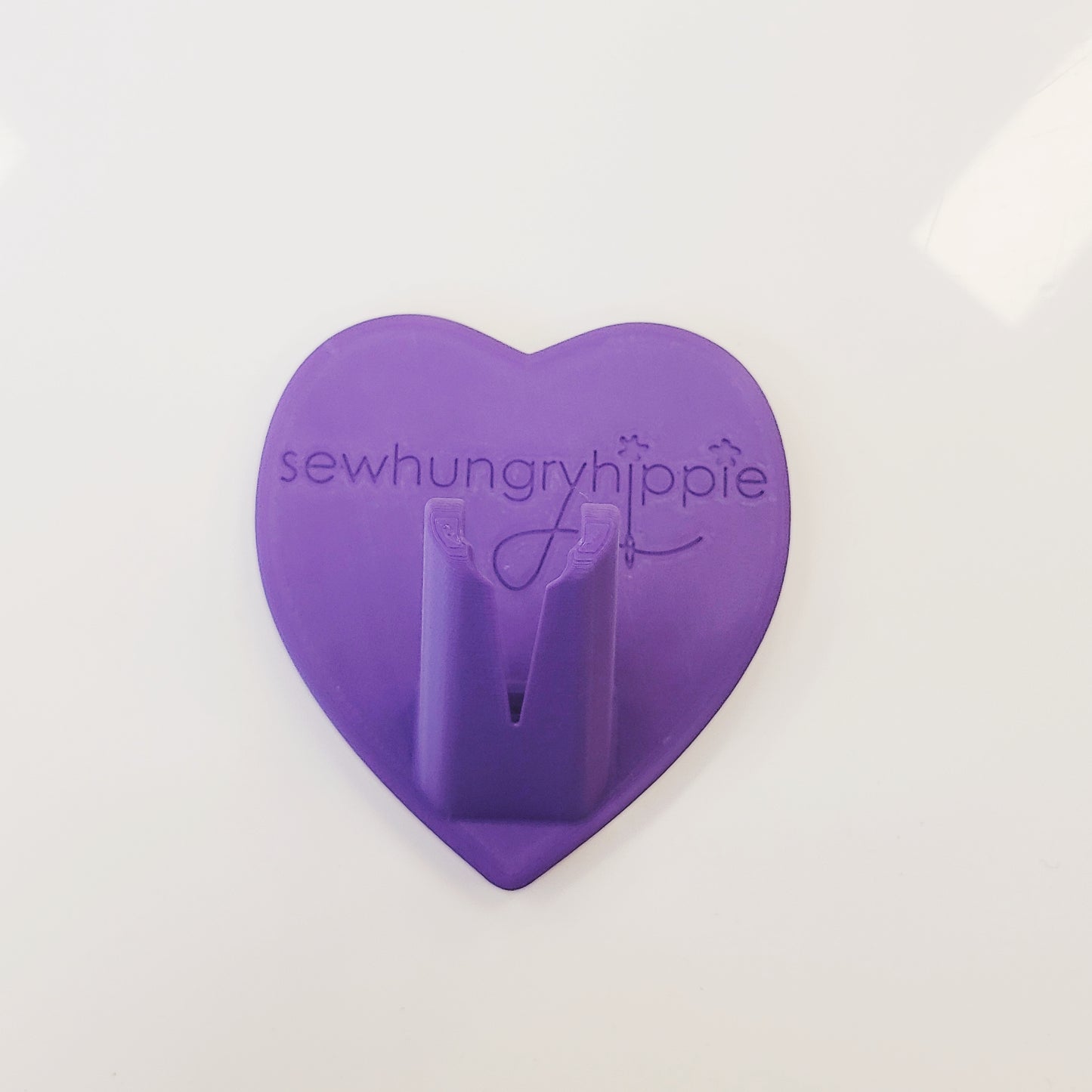 Purple heart-shaped sewing tool holder with text.
