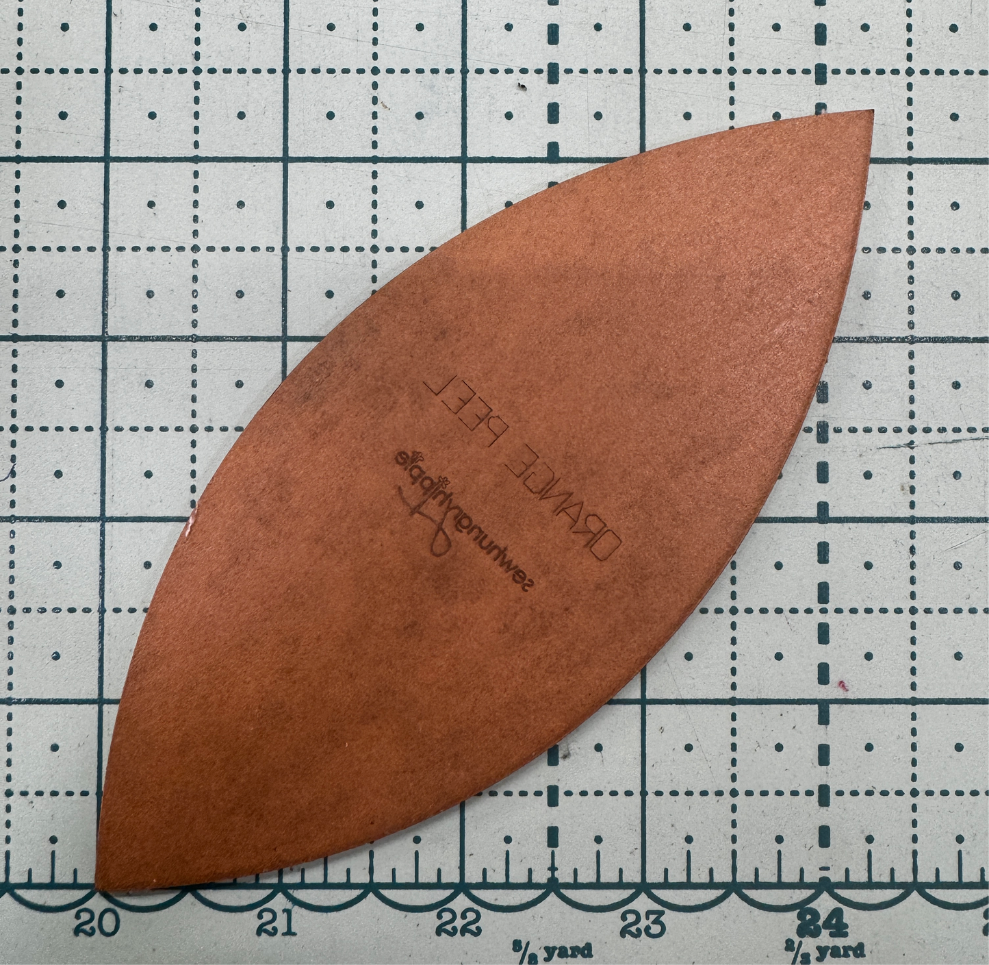 Brown, leaf-shaped craft template on a grid.