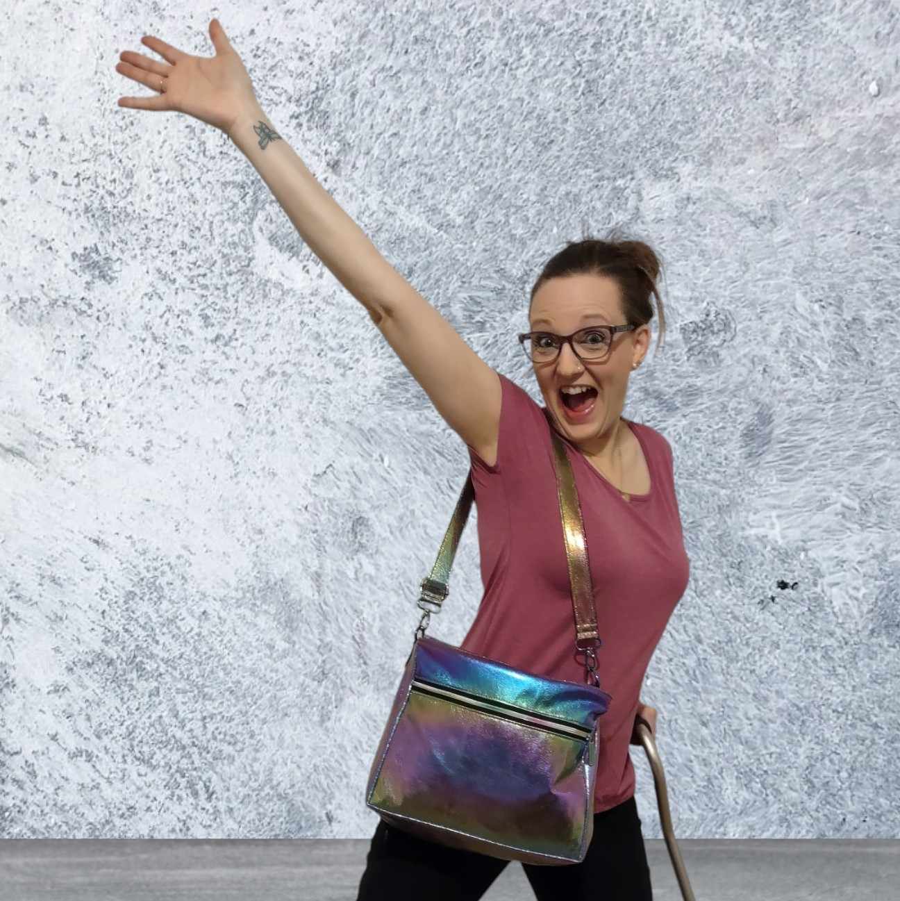 Woman with glasses and a bag, arm raised.