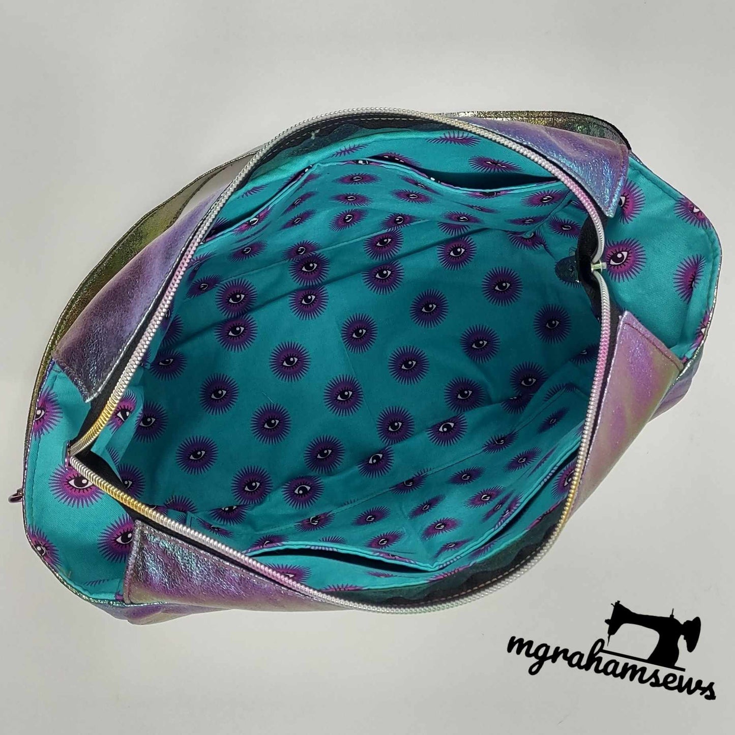 Open iridescent handbag with eye-print lining.