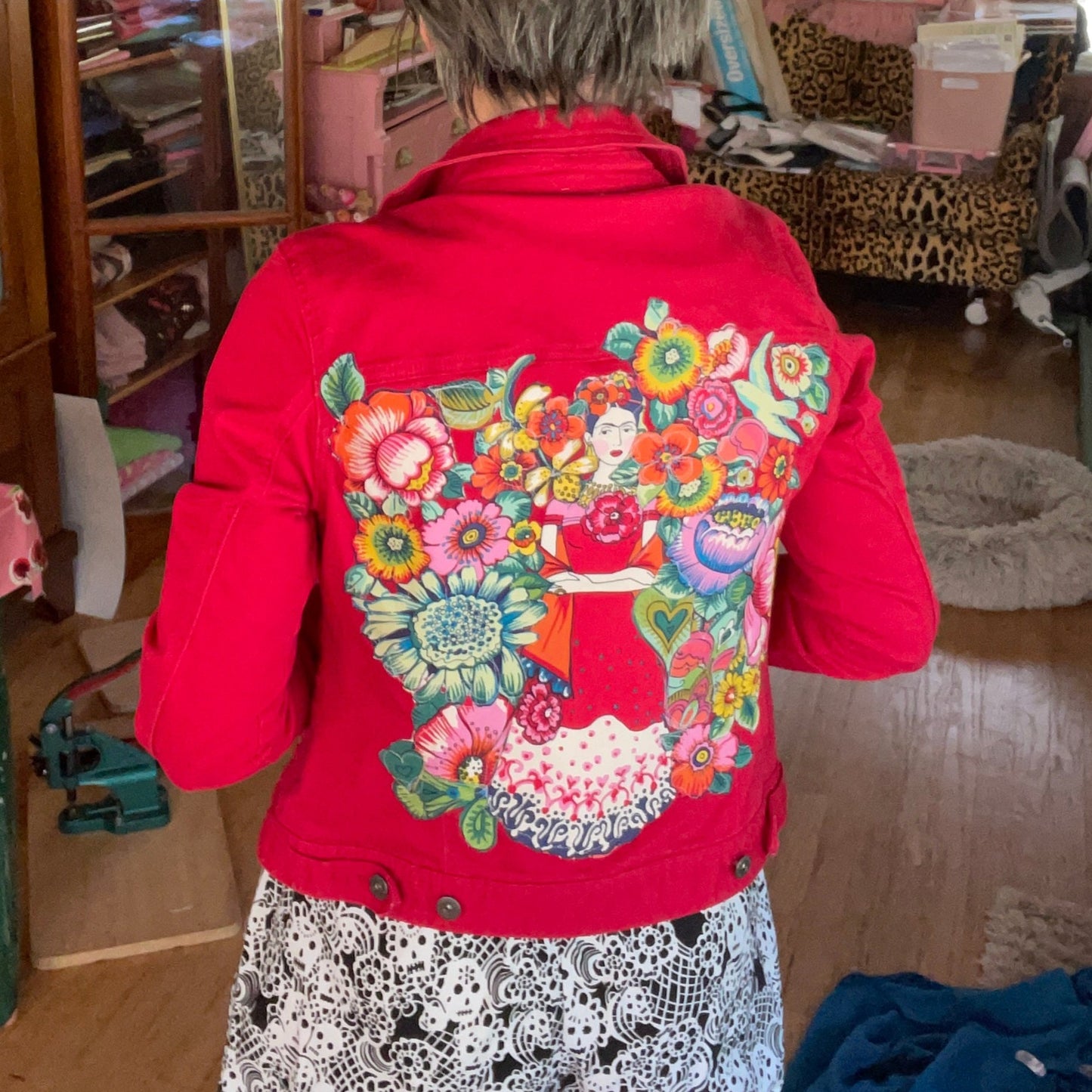 Woman in red jacket with floral art on back.