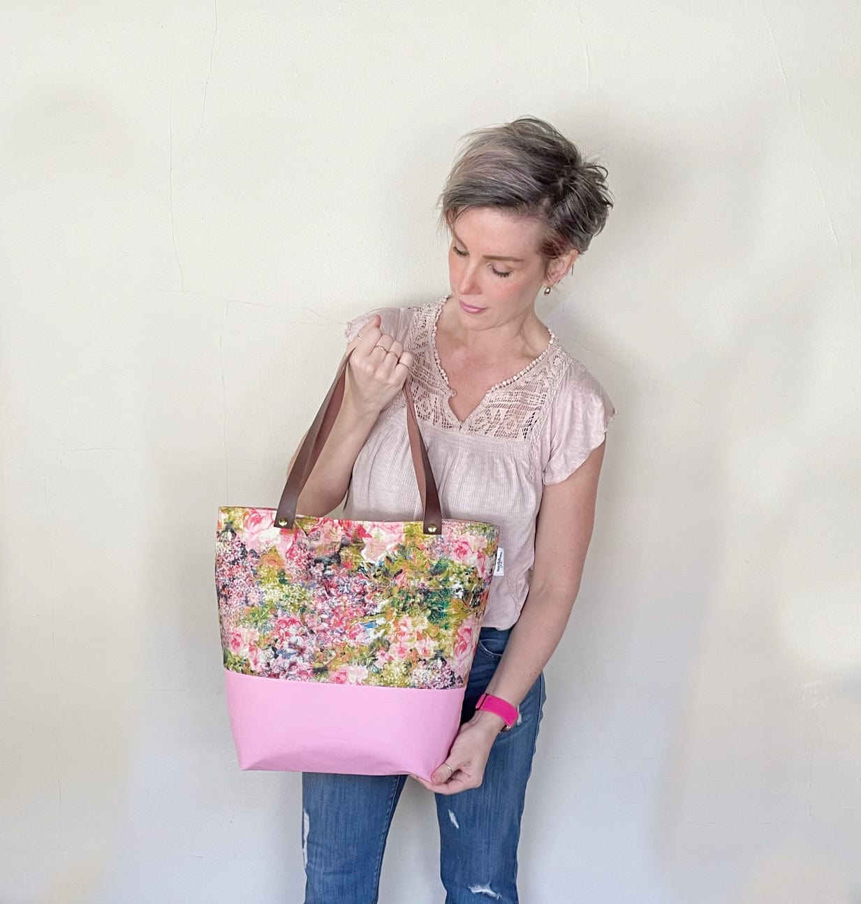 Woman holding a pink and floral tote bag.