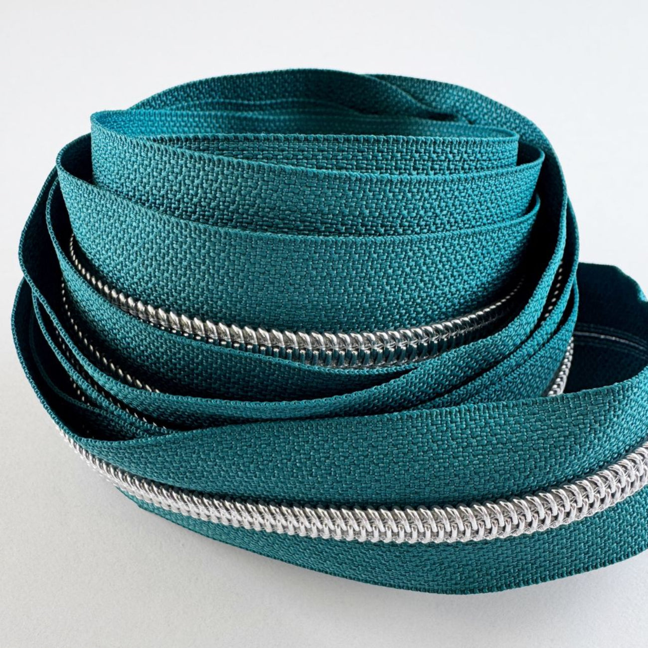 #5 continuous jade green zipper tape by the yard with shiny silver teeth for custom bags and pouches.