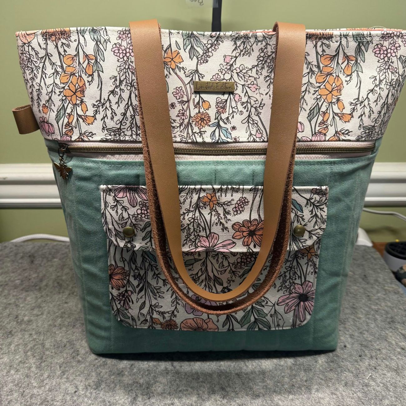 Floral-patterned bag with a teal base on a gray surface