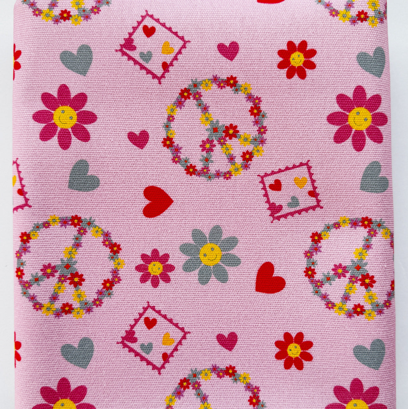 Pink canvas fabric featuring a retro floral peace sign pattern with red hearts and smiley face flowers.