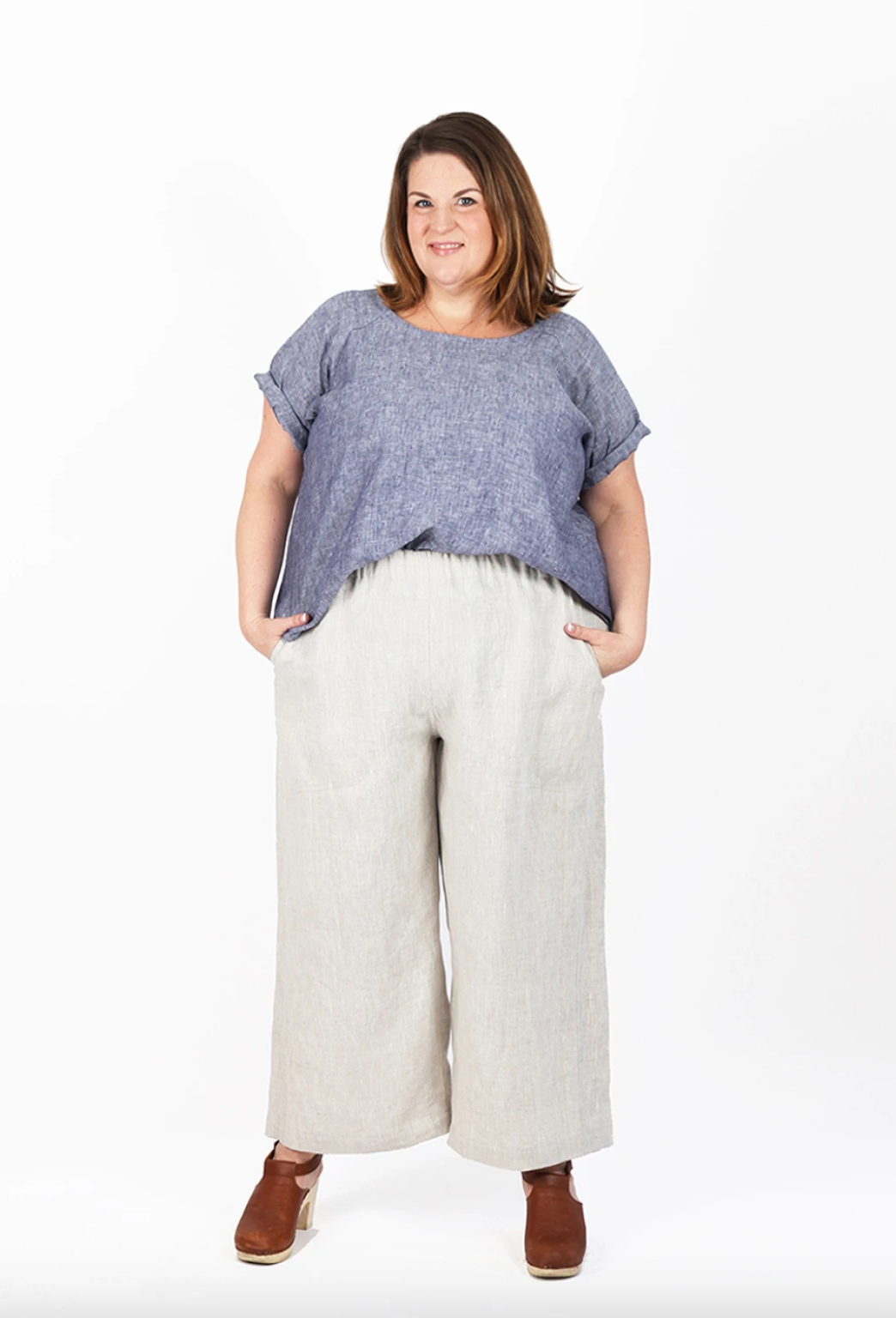 Woman wearing a blue top and white pants on a white background