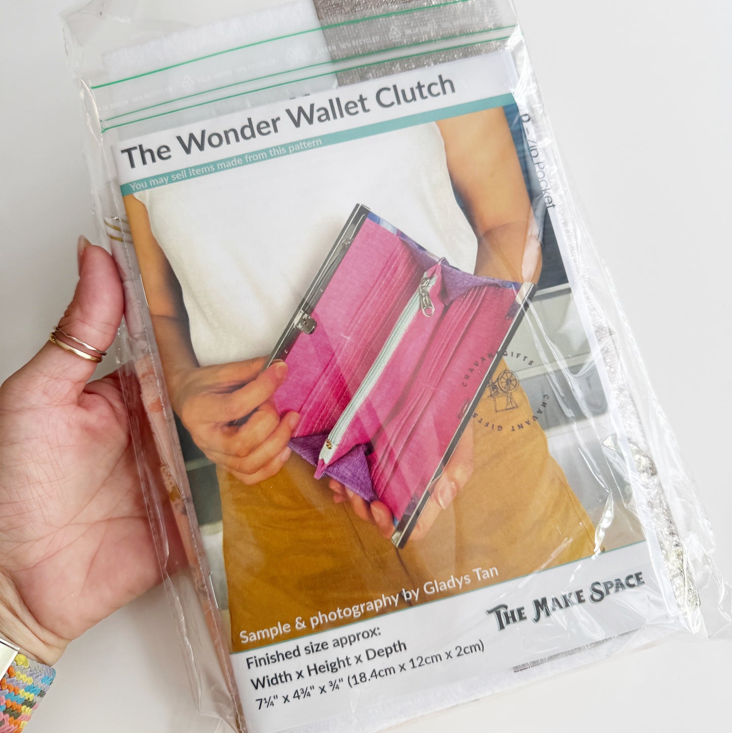 Packaged 'The Wonder Wallet Clutch' with a hand holding it, on a white background.
