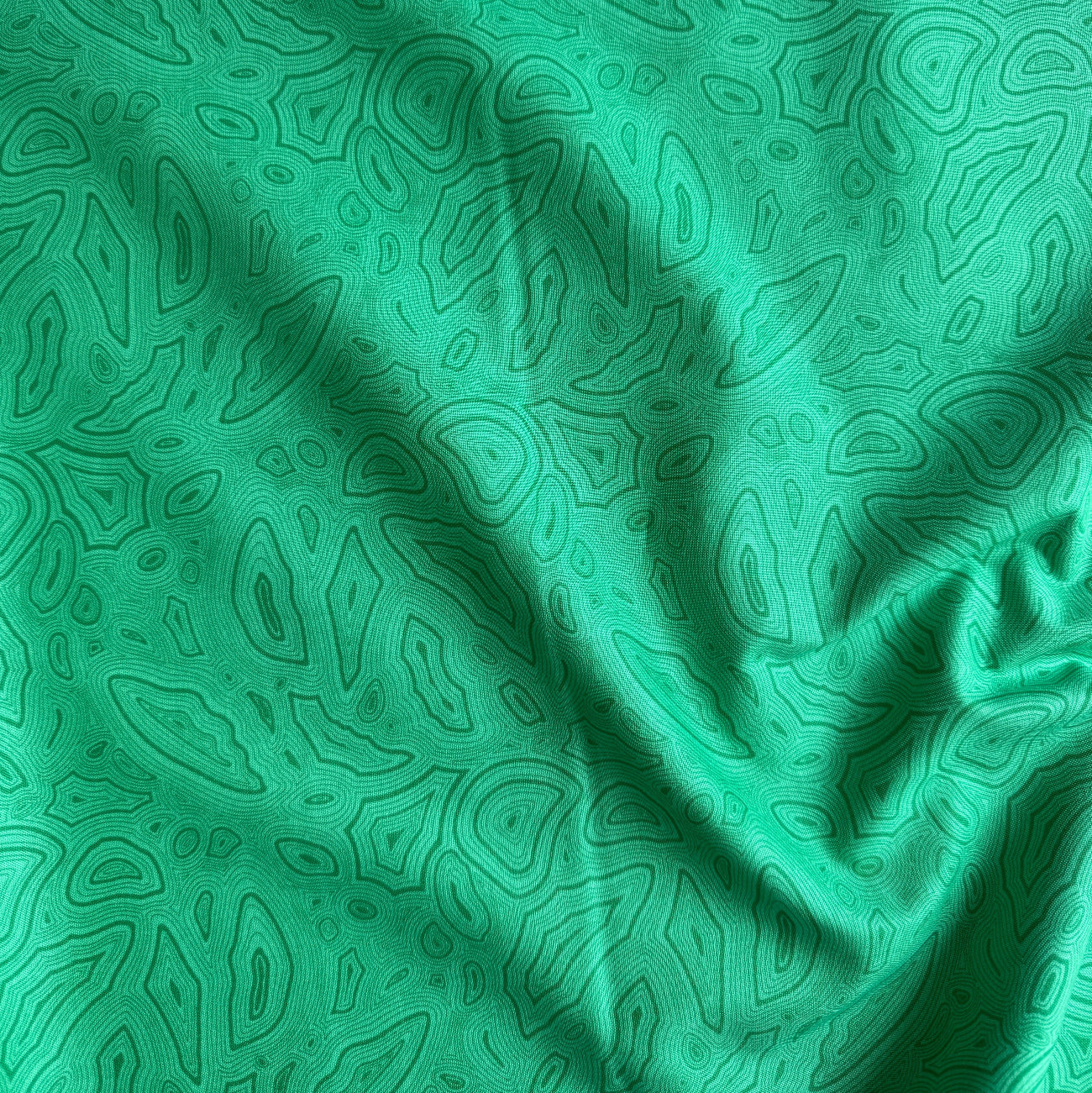 Draped and folded vibrant green fabric with a dark green malachite swirl pattern, showing the material's texture and sheen.