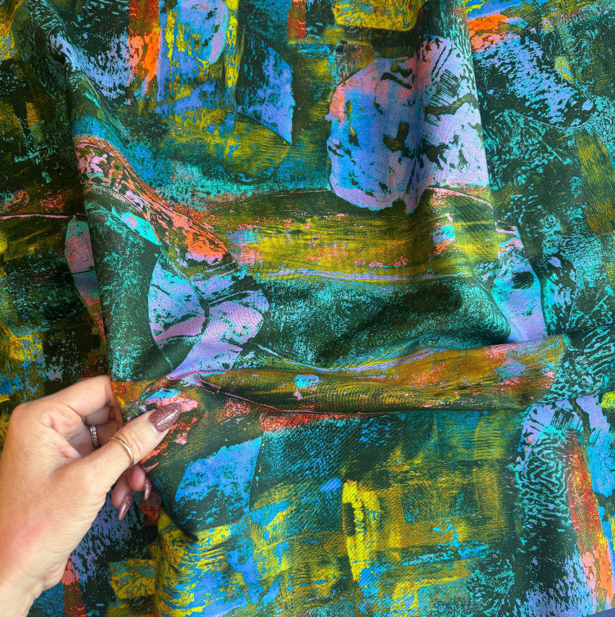 Colorful abstract painting with a hand holding a paintbrush