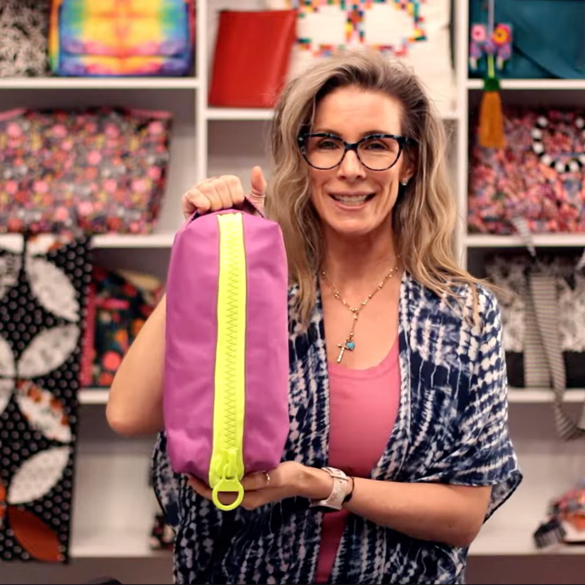 Woman holding an oversized pouch with a chunky neon yellow zipper and matching loop handle