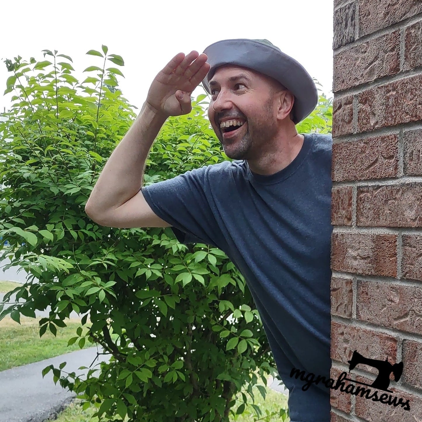 Graham wearing hat, looking out from brick wall