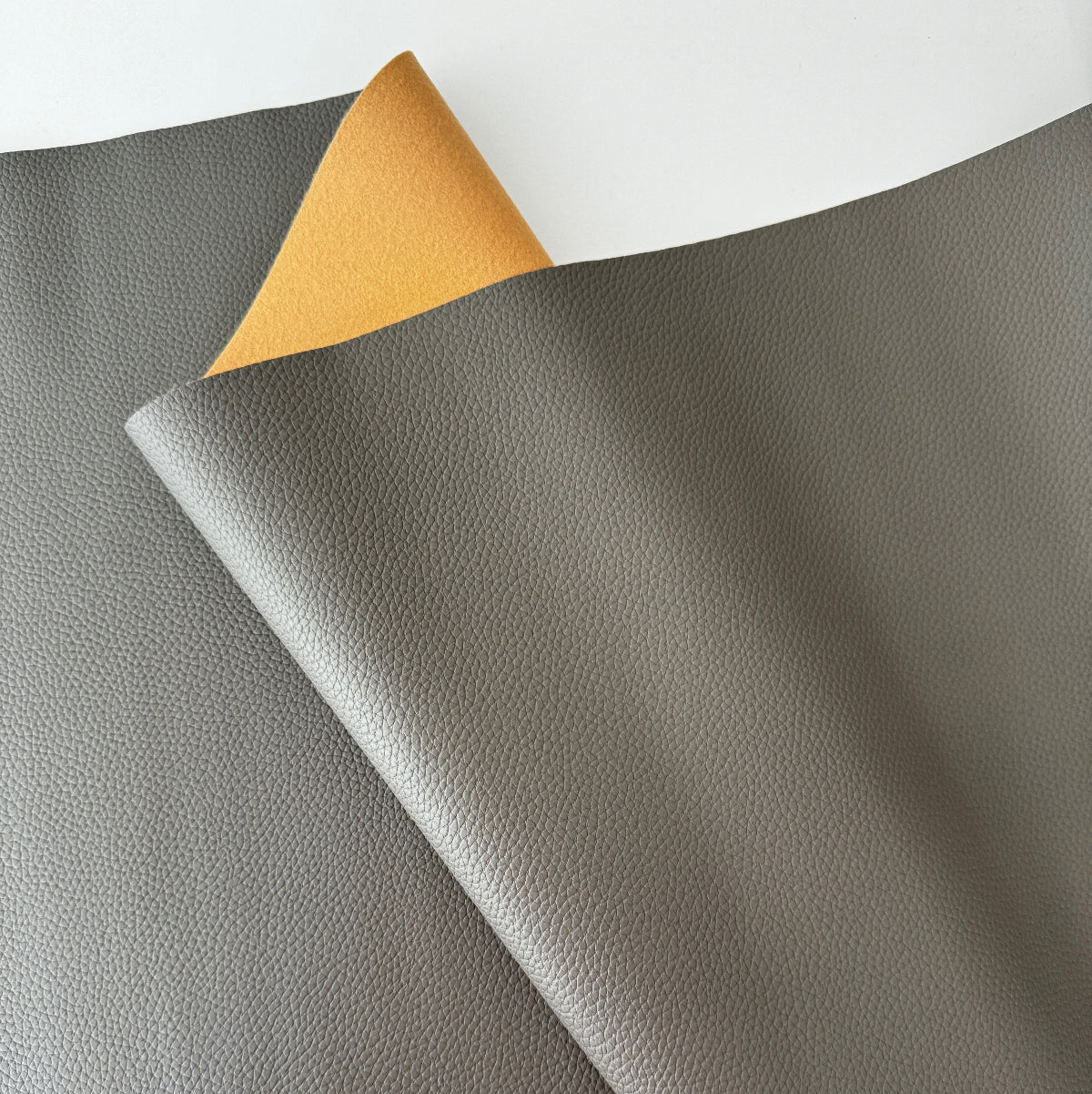 Gray leather fabric with a yellow corner on a white background