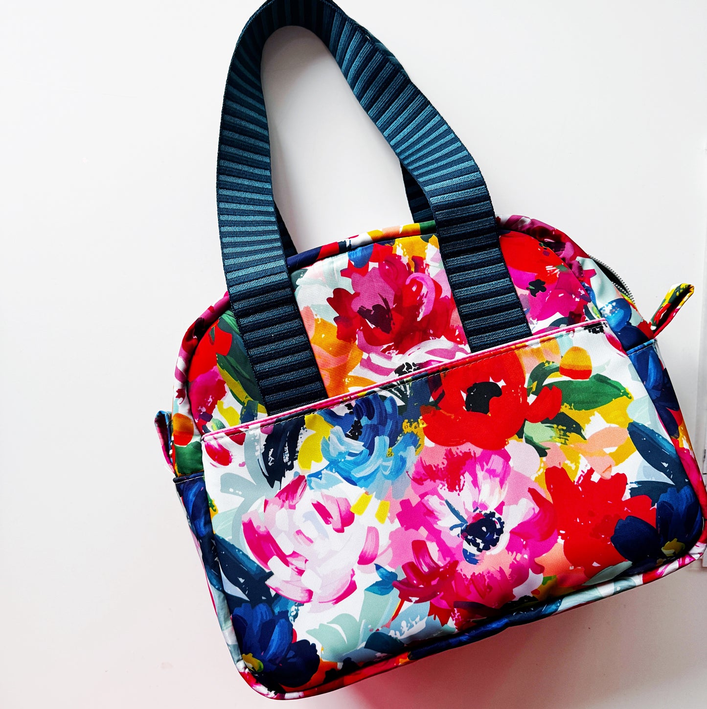 Colorful floral-patterned bag with a black strap on a white background