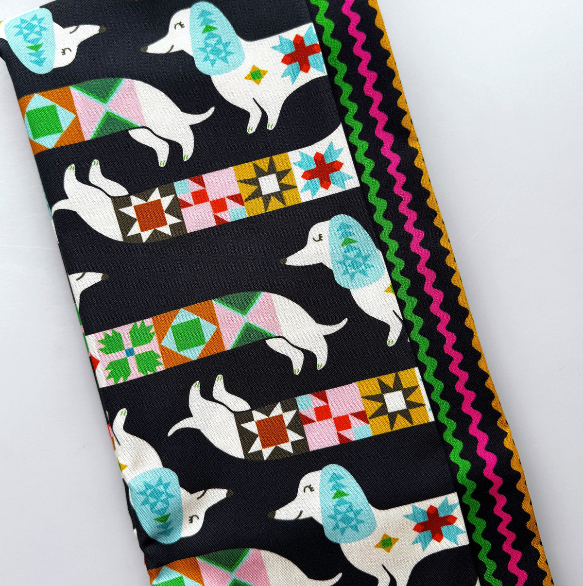 Ruby Star Society dachshund print fabric with colorful geometric patterns and multicolor ric rac trim for sewing.