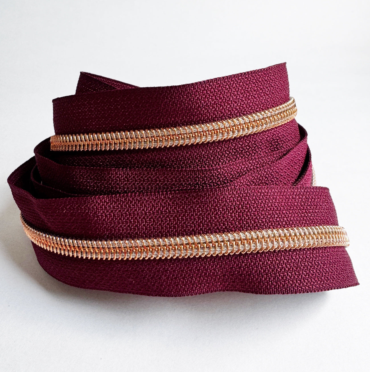 3-yard cut of #5 wine red continuous nylon zipper tape with rose gold teeth for handbags, purses, wallets, pouches, and bag making sewing projects.