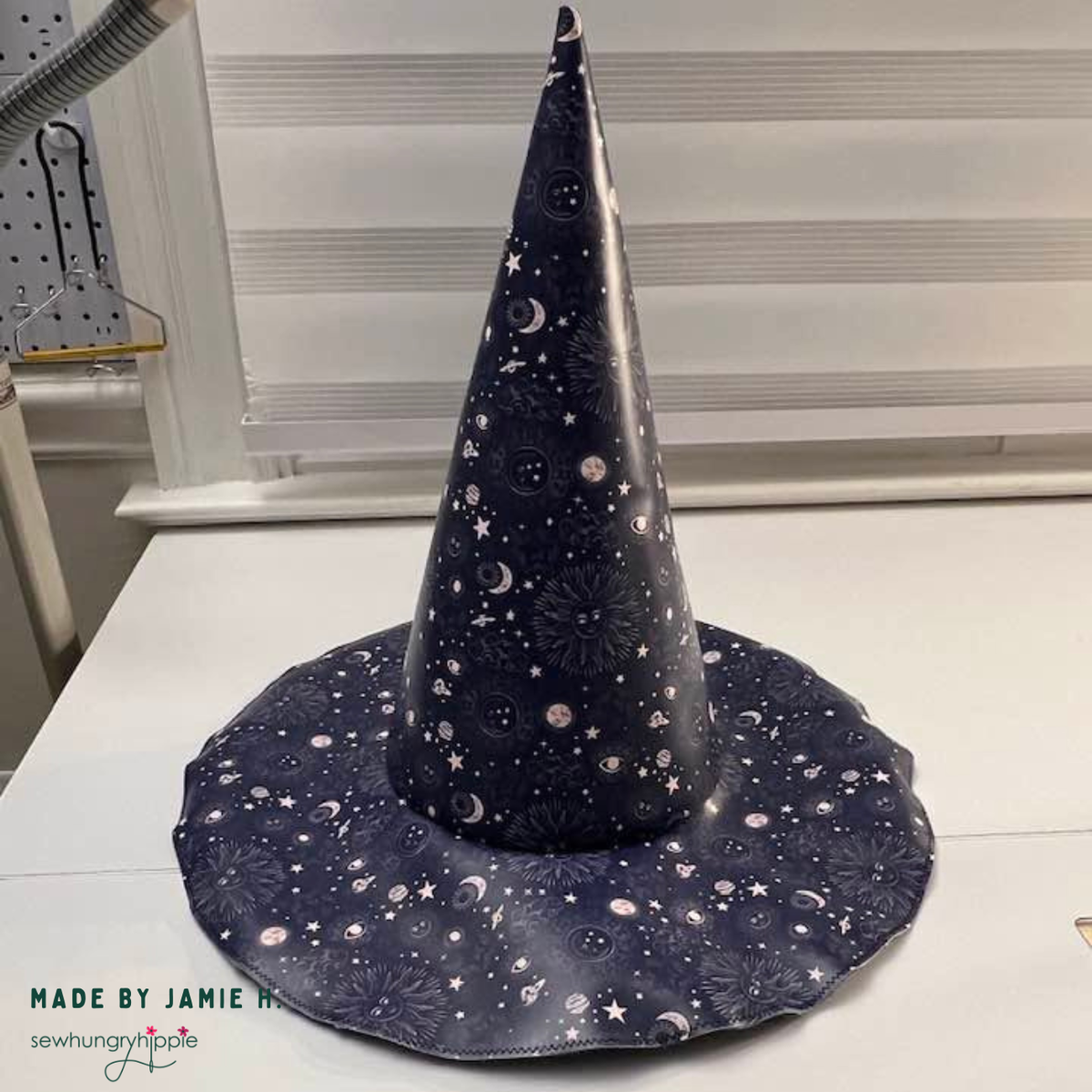 Sew Hungry Hippie witchy hat pattern in a pointed wide brim hat in dark navy celestial fabric with metallic suns, moons, and stars vinyl print