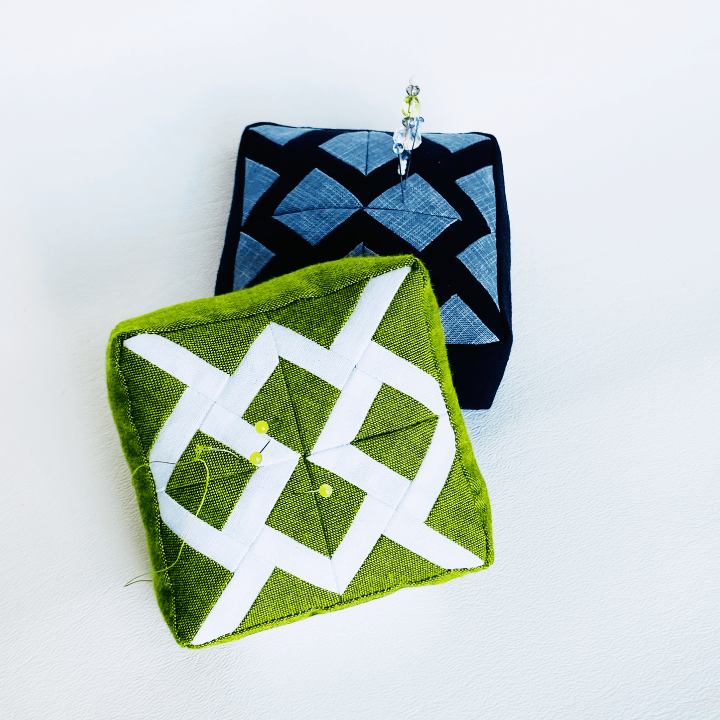 Two geometric patterned pincushions.
