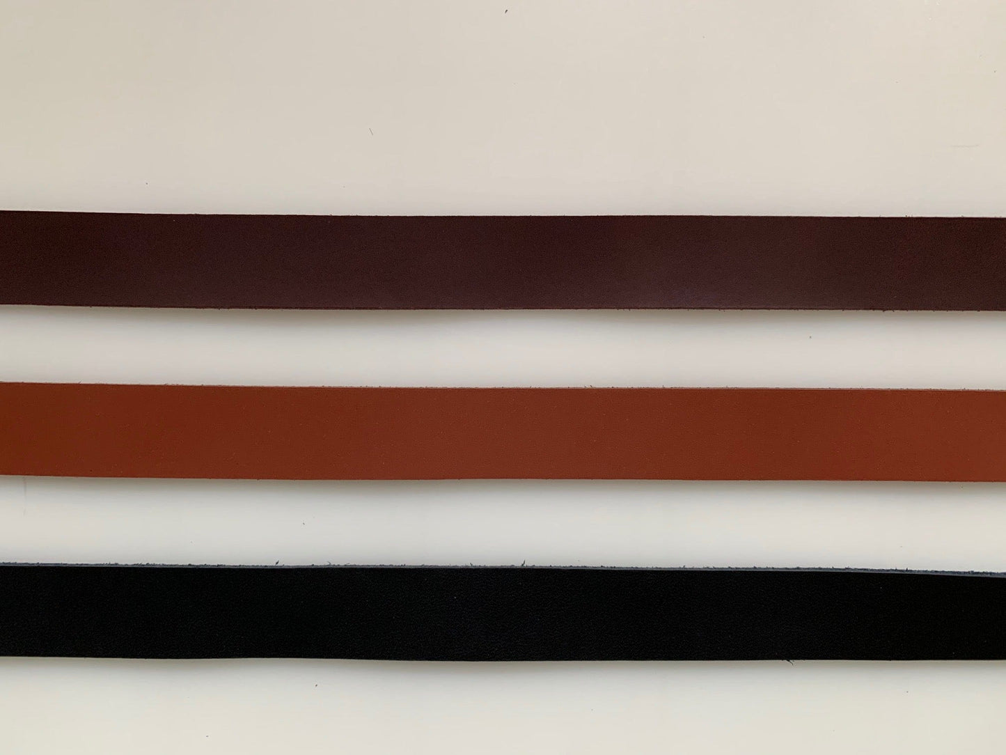 Three leather belts, brown, tan, and black.
