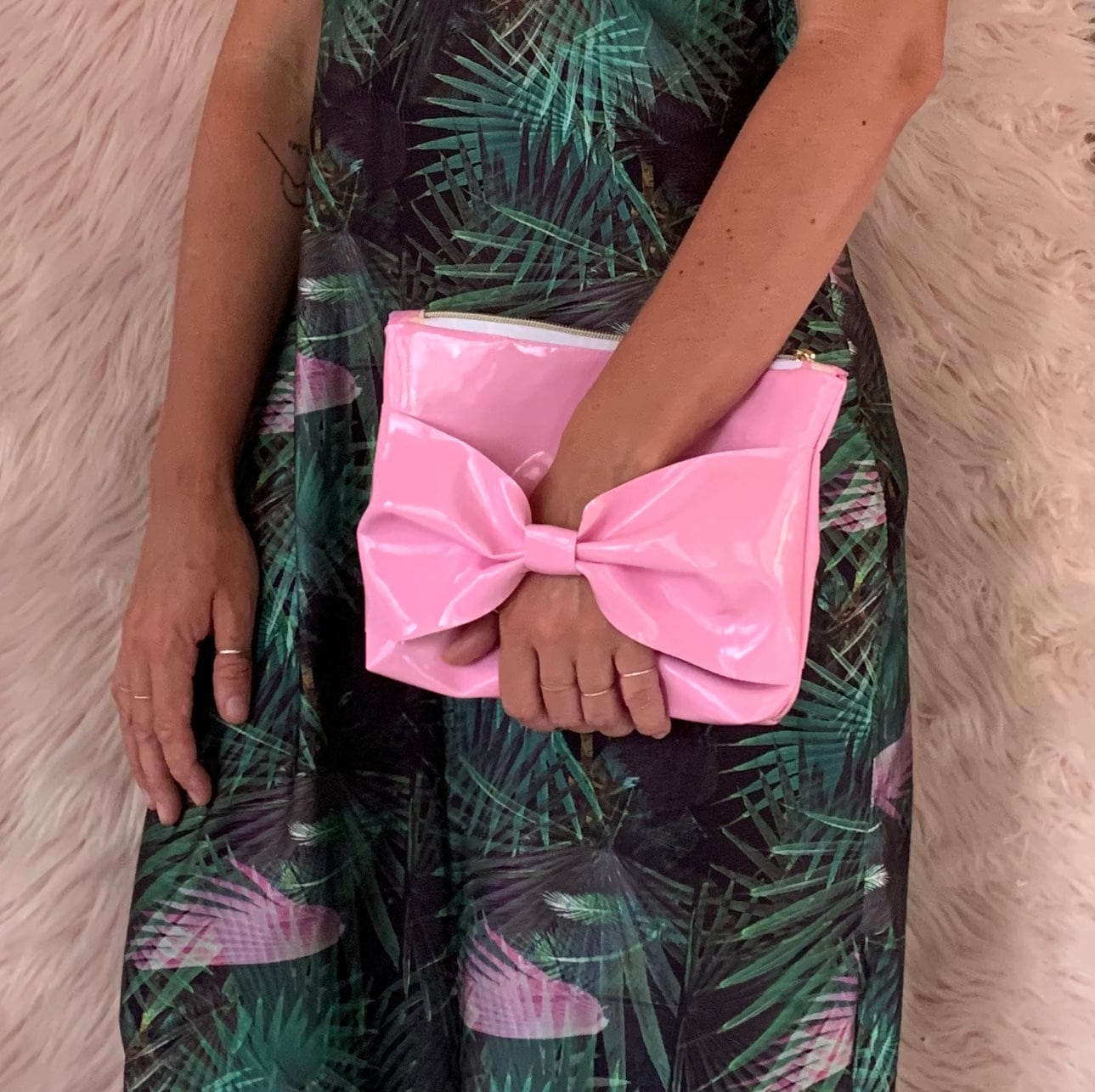 Woman holding a pink bow-shaped clutch bag.
