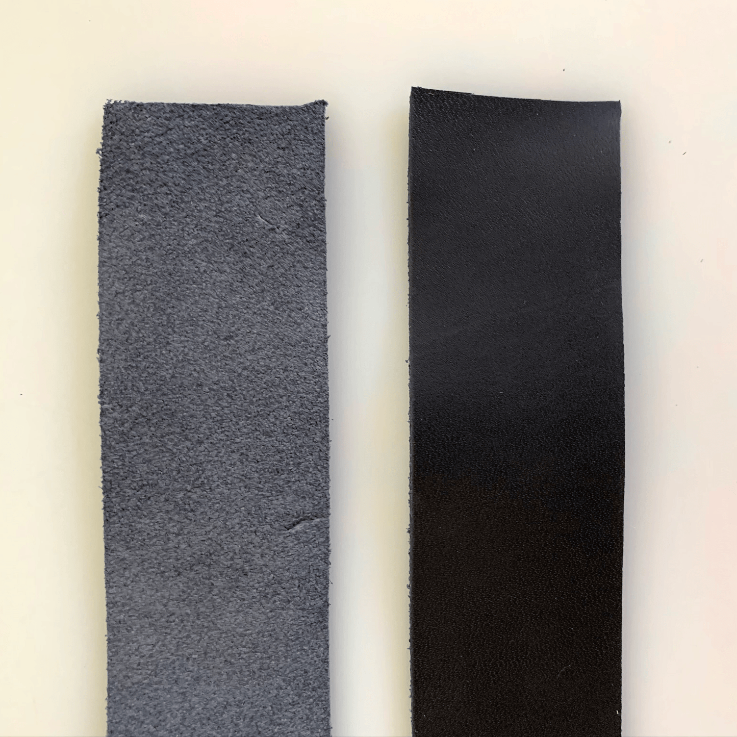 Two strips of leather, one rough and gray, one smooth and black.