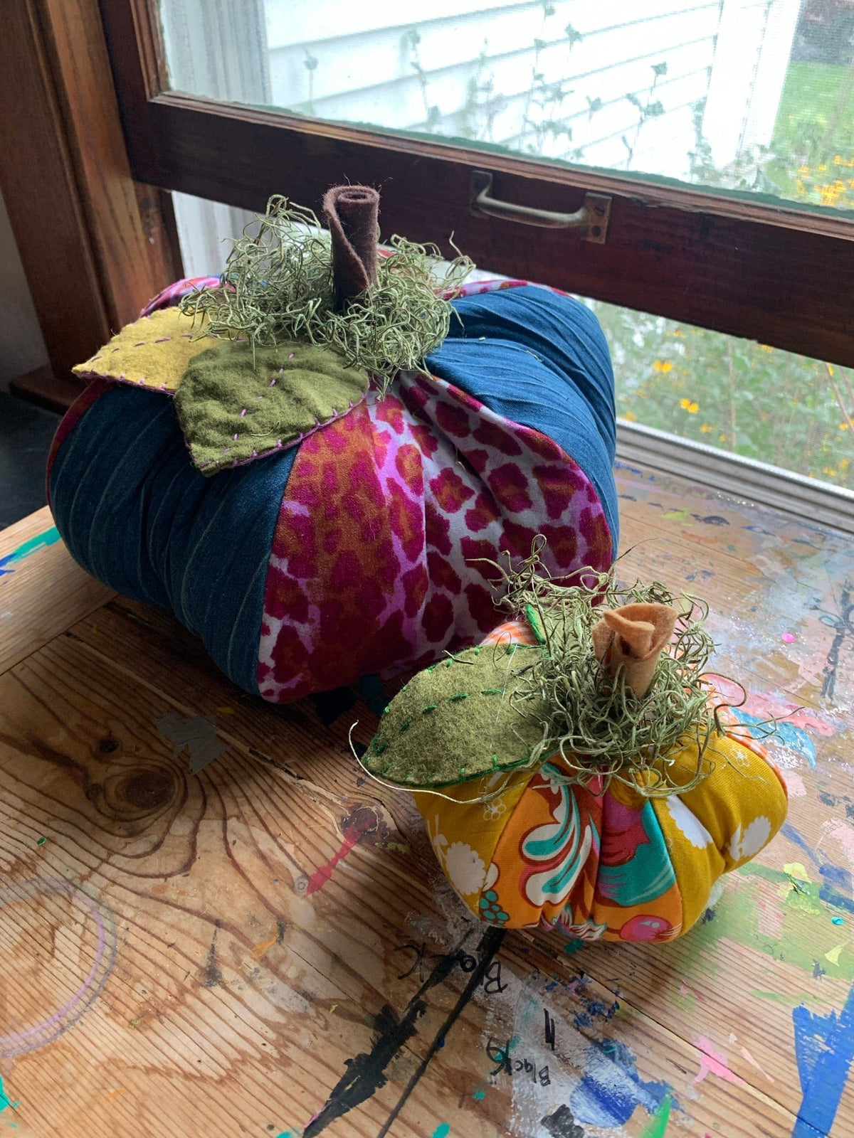 Two fabric pumpkins on a wooden surface.