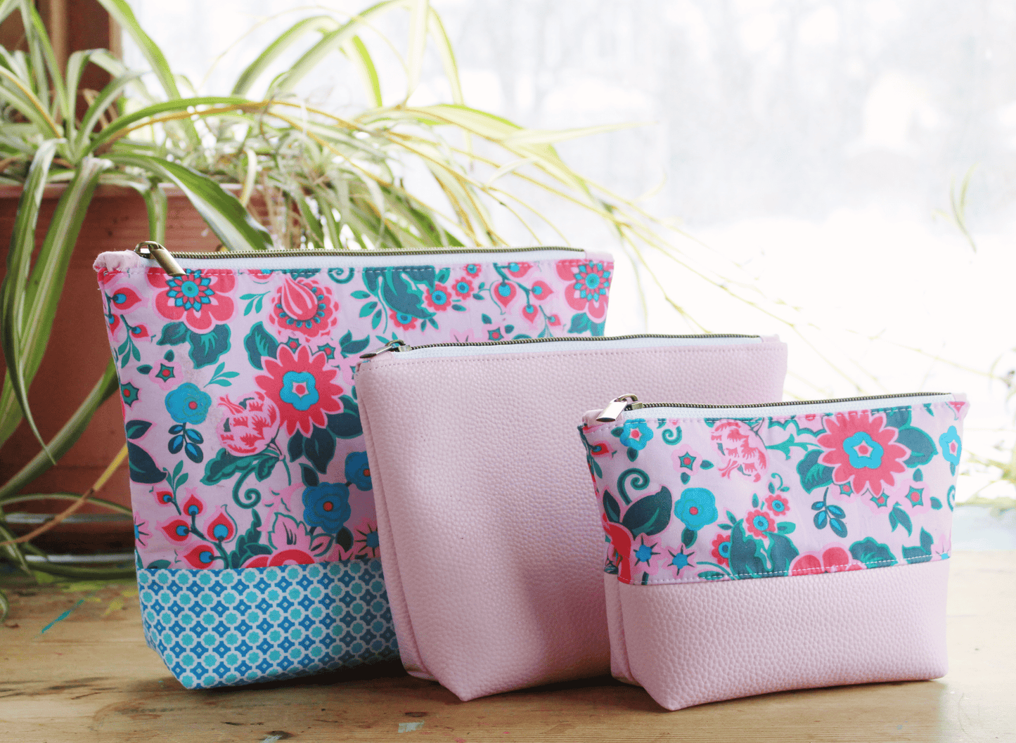 Three pink floral patterned cosmetic bags.