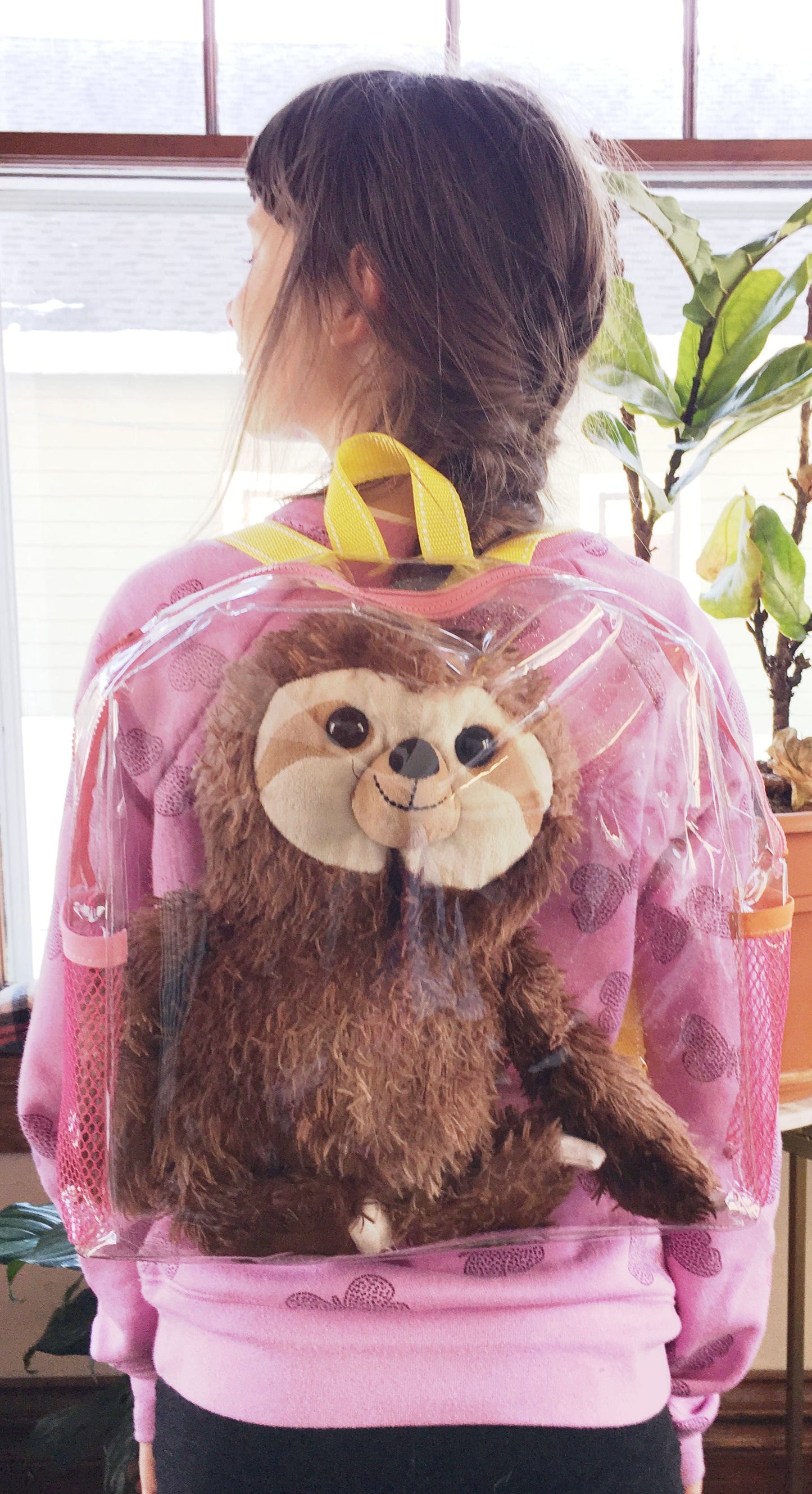 Girl wearing clear sloth backpack