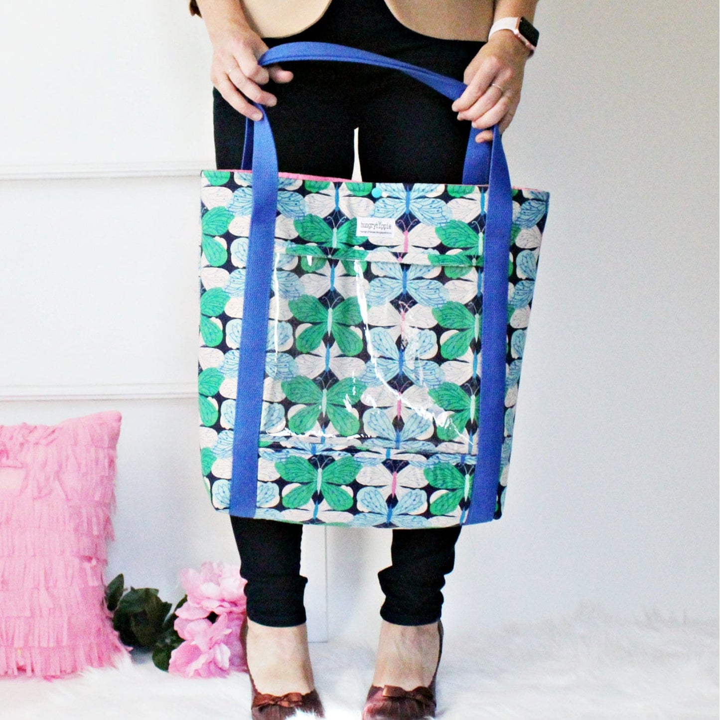 Essentials tote bag with blue handles and floral pattern.