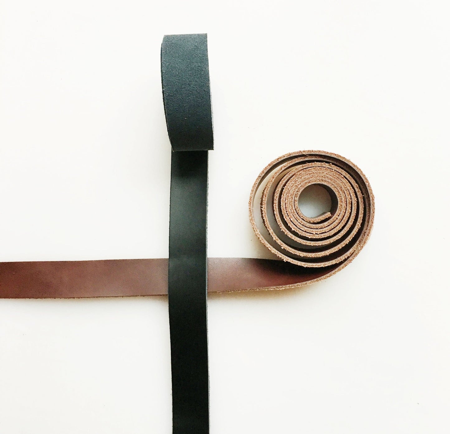Brown and black leather strips, rolled and flat.