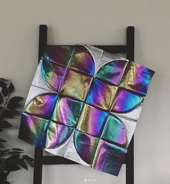 Iridescent patterned quilt draped on a ladder.