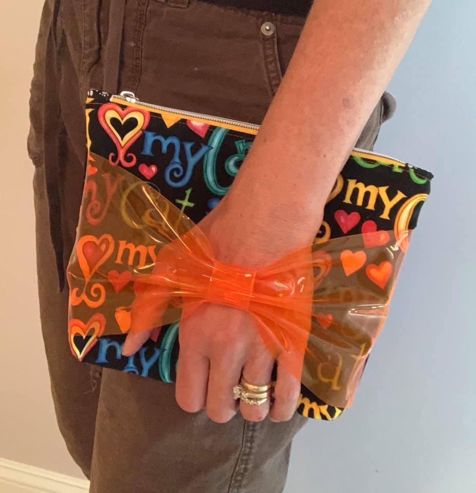 Stef2 holding colorful clutch with bow