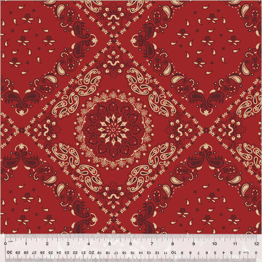 Traditional bandana-style quilt backing fabric featuring a large, intricate central mandala emblem enclosed in a diamond trellis pattern. The design includes classic paisley motifs, small stars, and floral elements in cream and dark burgundy-red over a rich crimson red background.