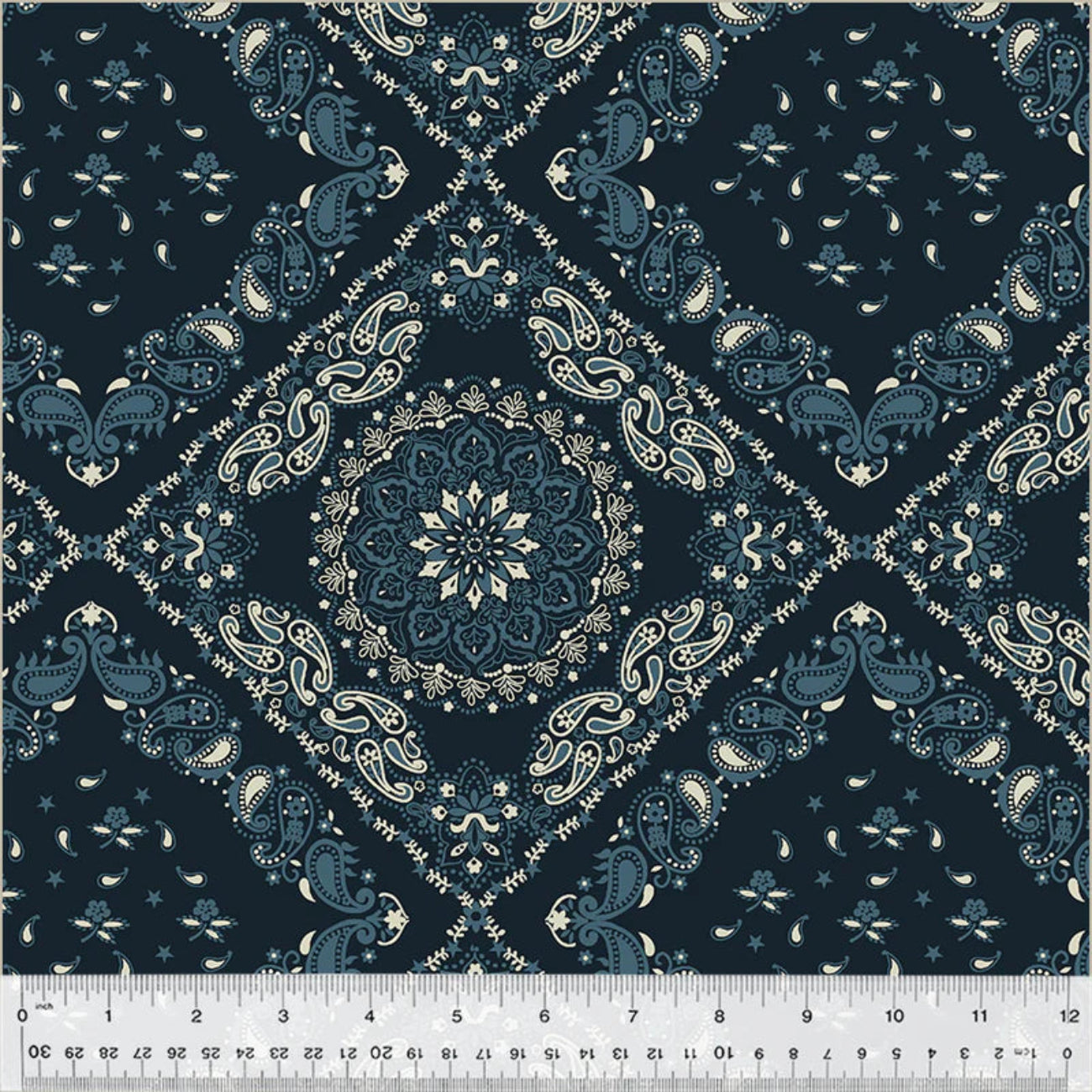 Classic bandana-style quilt backing fabric showcasing a large central mandala framed by a geometric diamond lattice. The detailed pattern features traditional paisley teardrops, tiny stars, and delicate flourishes in cream and slate blue over a dark navy blue background.
