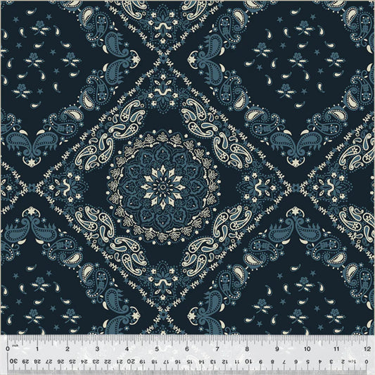 Classic bandana-style quilt backing fabric showcasing a large central mandala framed by a geometric diamond lattice. The detailed pattern features traditional paisley teardrops, tiny stars, and delicate flourishes in cream and slate blue over a dark navy blue background.