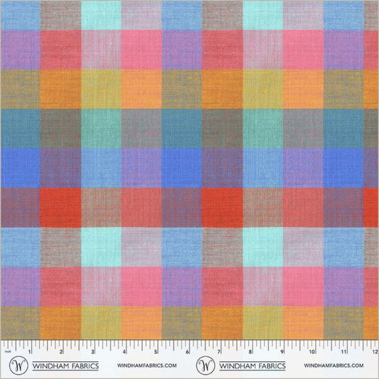 Vibrant rainbow plaid fabric by Windham Fabrics featuring a large-scale gingham or check pattern. The woven texture blends overlapping bands of bright coral red, sunny orange, grassy green, sky blue, and hot pink, complete with a fabric ruler salvage edge at the bottom.