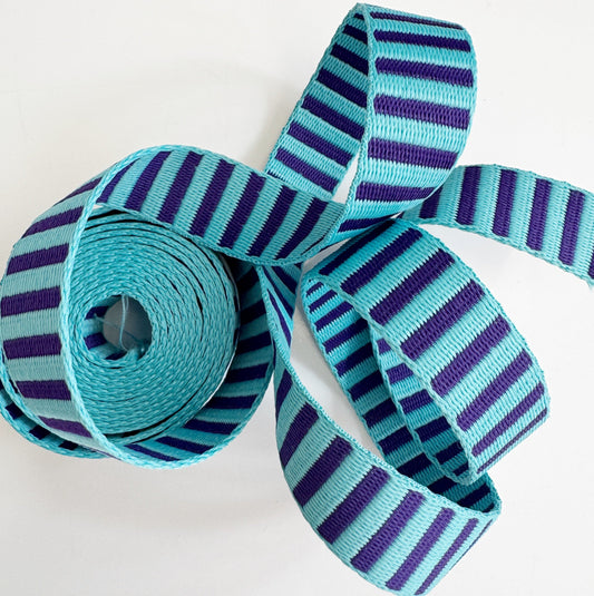 Coiled 1-inch wide woven striped webbing in teal blue and deep purple for bag straps.