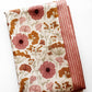 a vintage-style botanical floral pattern in muted pink and rust-orange tones on a cream background and a coordinating fabric yard in orange striped