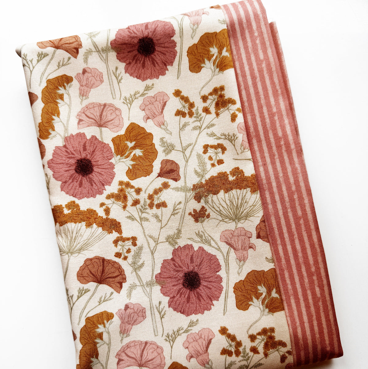a vintage-style botanical floral pattern in muted pink and rust-orange tones on a cream background and a coordinating fabric yard in orange striped