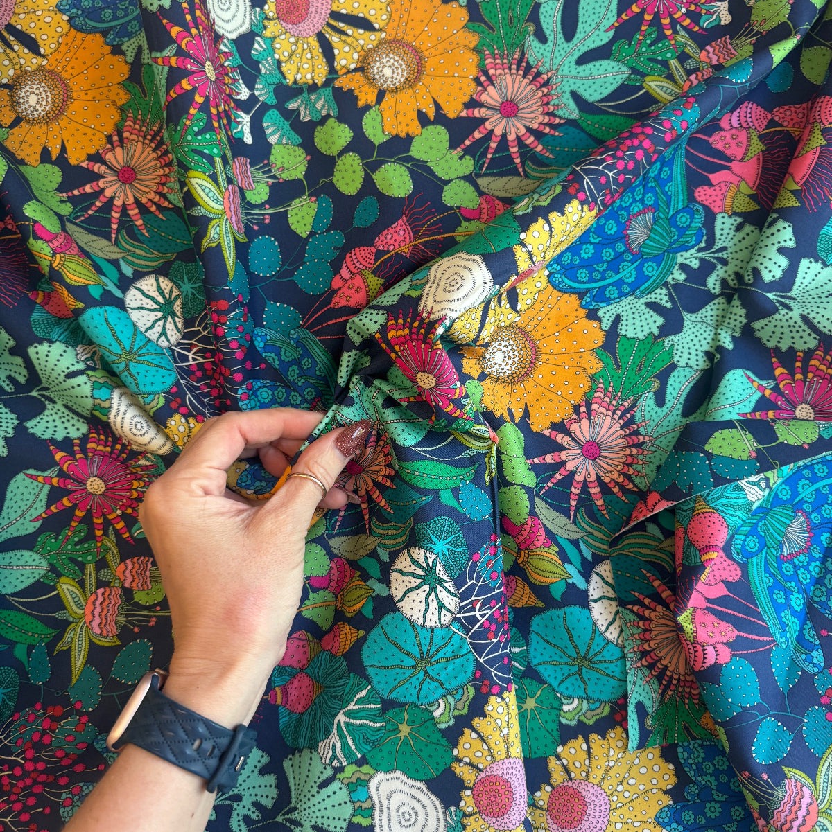 Colorful floral fabric with a hand holding it