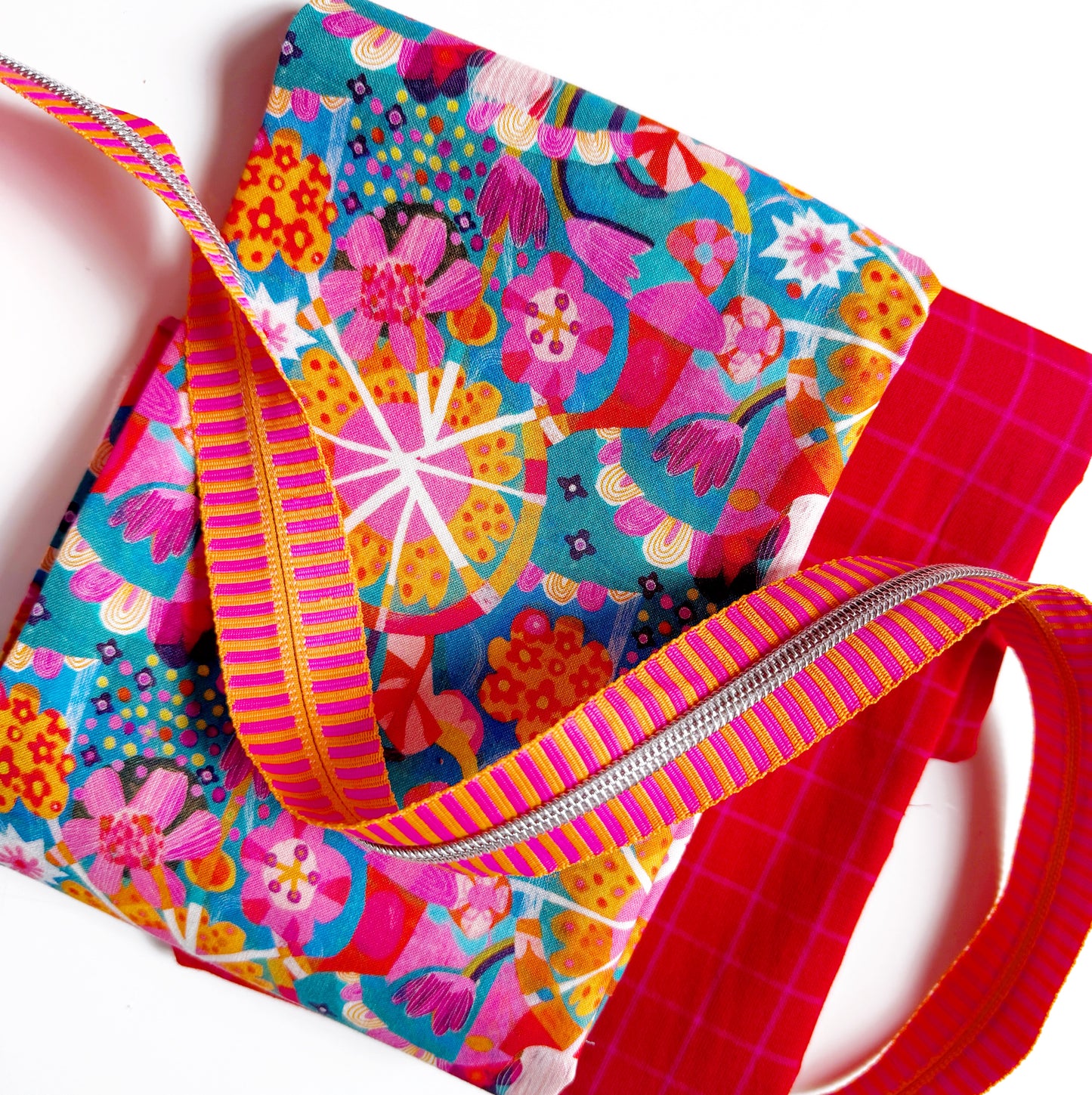 Vibrant sewing kit with Este MacLeod Star Multi fabric, Ruby Star Society red grid plaid, and pink and orange striped zipper tape by SewHungryHippie.