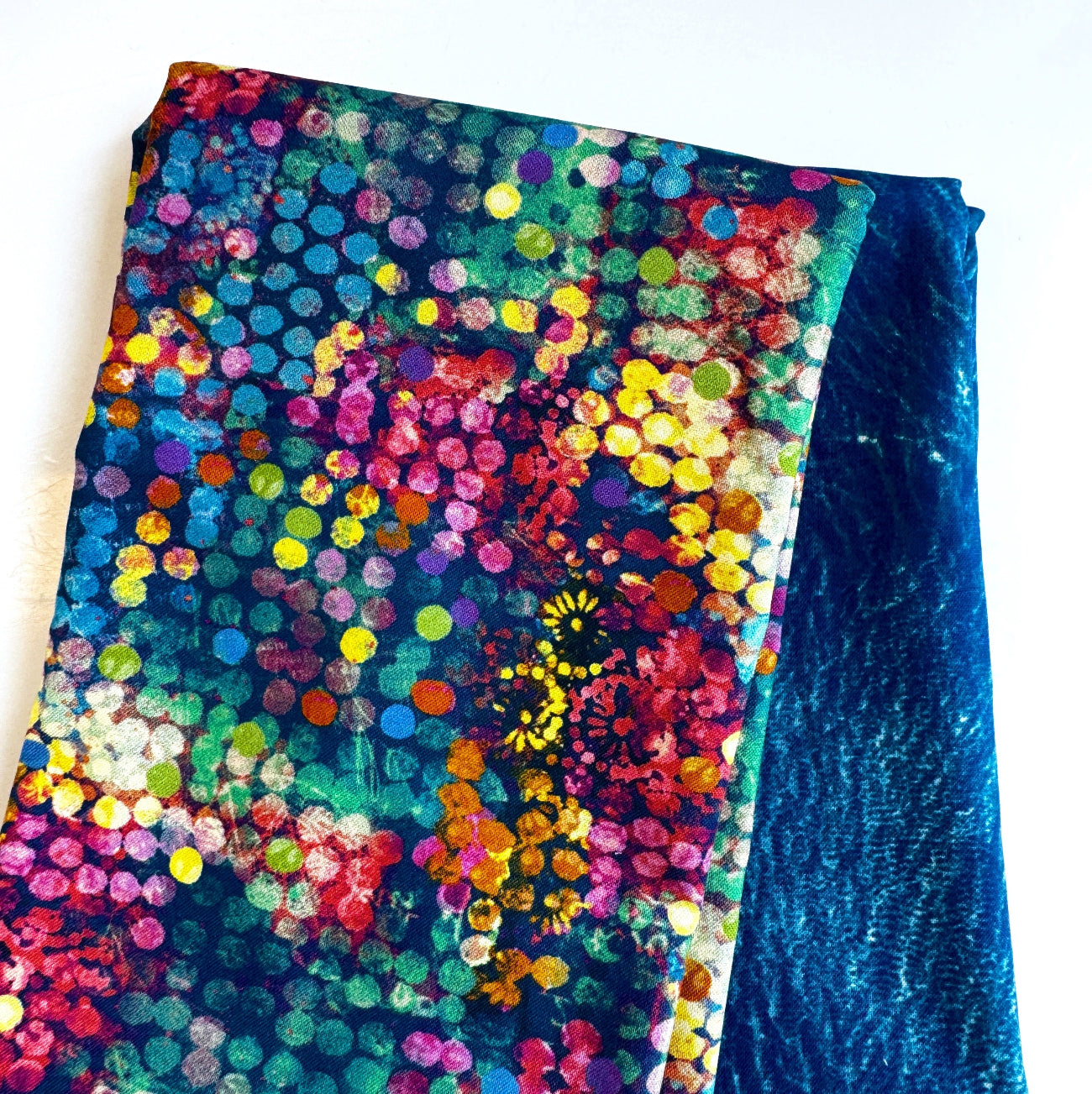 Vibrant multi-color abstract millefiori mosaic dot print fabric paired with a coordinating deep ocean blue textured batik canvas fabric for quilting and handmade bag making.