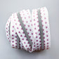 A coiled roll of white zipper tape trim featuring a pattern of small pink hearts, with a silver metal zipper running down the center, set against a plain light gray background.
