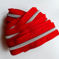A coiled bundle of bright red zipper tape with silver metal teeth, photographed on a plain light background.