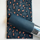 Charcoal gray and muted coral ikat leopard print cotton fabric paired with a coordinating dark teal pebbled faux leather roll for handmade bag making and sewing crafts.
