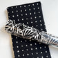 Black and white polka dot cotton fabric paired with a matching bold black and white floral botanical patterned vinyl roll for handmade bag making and sewing projects.