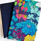 Vibrant multi-color whimsical botanical print fabric featuring bright blue flowers and lime green ginkgo leaves, paired with a solid dark navy blue canvas base fabric for sewing and bag making.