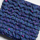 Stack of blue fabric with pink and green patterns on a white background