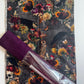 A spooky autumn-themed craft bundle with skull, mushroom, and crow print fabric alongside a roll of rich violet faux leather vinyl